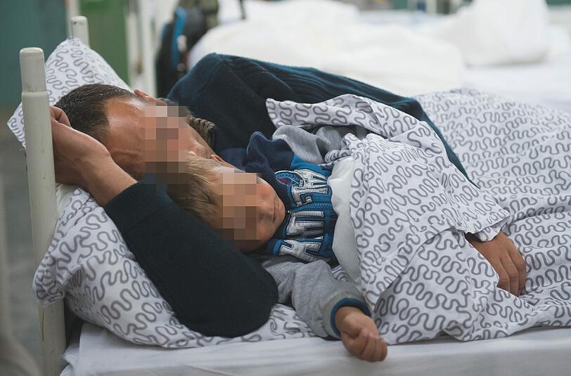 Ein Flüchtling teilt sich mit seinem Sohn ein Bett in der Bayernkaserne. Seit vielen Wochen ist dort der Platz knapp.