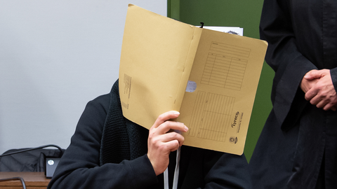 Der Angeklagte verbirgt sein Gesicht.