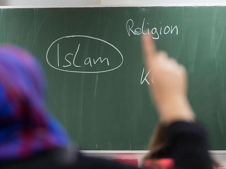Eine Schülerin mit Kopftuch meldet sich an einer Schule bei einer Unterrichtsstunde zum Thema Islam. Foto: Frank Rumpenhorst/Archiv
