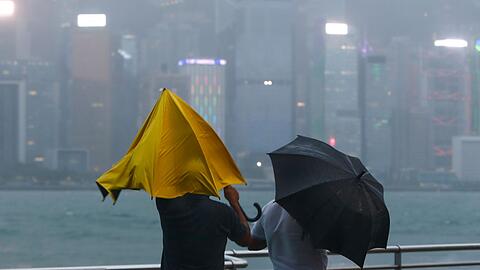 Menschen mit Regenschirmen kämpfen in Hongkong mit starkem Wind und Regen des Taifuns "Saola".