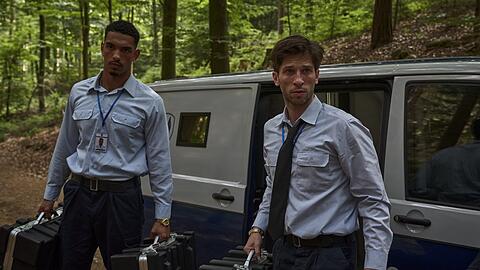 "Der Millionen Raub": Omar Abdallah (Karim Ben Mansur) und Zlatko Petrovic (Slavko Popadić) stehen mit jeweils zwei Koffern in der Hand vor einem Geldtransporter.