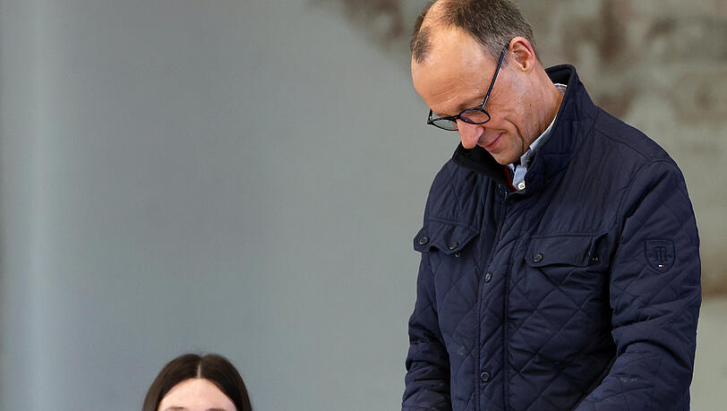 Friedrich Merz (CDU, r), Parteivorsitzender und Kanzlerkandidat, gibt im Wahllokal in der Schützenhalle Arnsberg-Niedereimer seine Stimme ab.