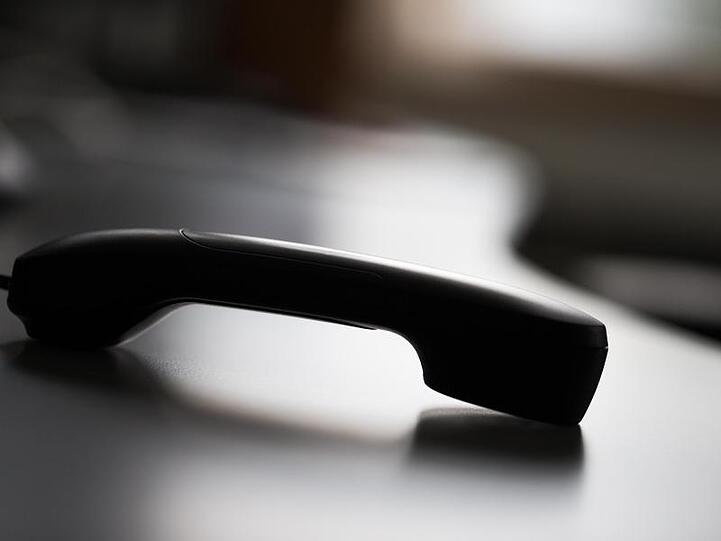 Ein Telefonhörer liegt auf einem Tisch. (Illustration)