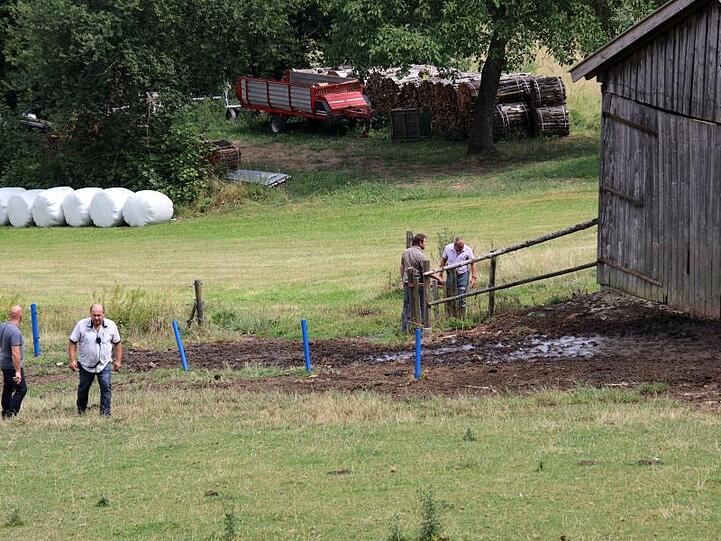 Polizisten in Zivil stehen auf einer Weide, auf der zuvor ein Stier zwei Menschen getötet hatte. Foto: Alexander Auer