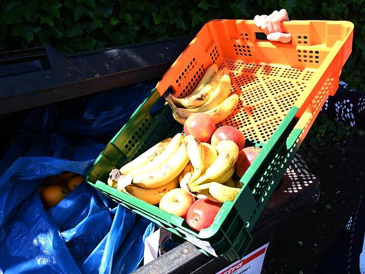 Ein Mitarbeiter eines Supermarktes bringt Obst zu einem Container. Foto: Carmen Jaspersen/dpa/Archiv/Illustration