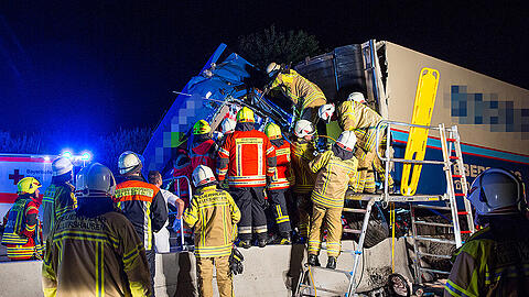 Einsatzkräfte der Feuerwehr arbeiten am 07.08.2015 auf der A9 bei Allershausen an einem verunfallten LKW. Der schwerverletzte Lenker des LKW ist zuvor auf ein Baustellenfahrzeug aufgefahren und danach in die Mittelleitplanke gekracht.