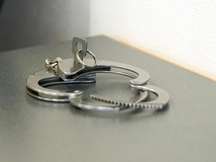 Handschellen liegen auf einem Tisch. Foto: Armin Weigel/dpa/Symbolbild