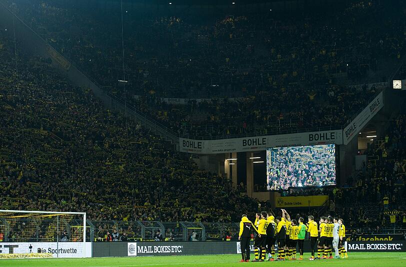 Dortmunds Fans halten ihre Schals in die Höhe und singen "You never walk alone" für einen Fan, der während des Spiels an einem Herzinfarkt gestorben war.
