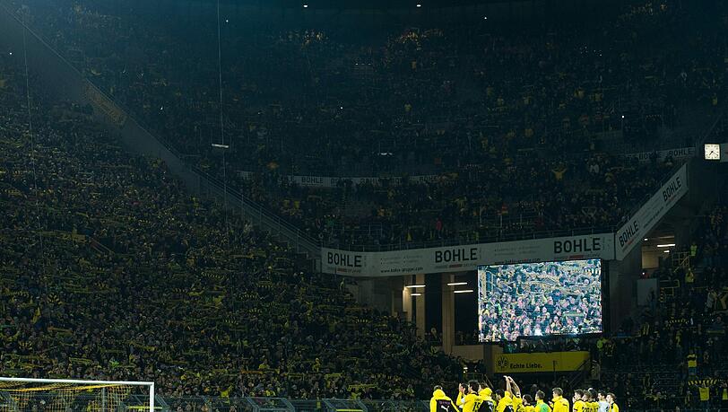 Dortmunds Fans halten ihre Schals in die Höhe und singen "You never walk alone" für einen Fan, der während des Spiels an einem Herzinfarkt gestorben war. Dortmunds Fans halten ihre Schals in die Höhe und singen "You never walk alone" für einen Fan, der während des Spiels an einem Herzinfarkt gestorben war.