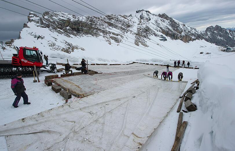 Arbeiter decken auf dem Zugspitzplatt bei Grainau den Gletscher mit einer Plane ab, um ein Abschmelzen zu verhindern. Deutschlands einziger Gletscher soll waehrend der warmen Sommermonate mit der 500 bis 600 Quadratmeter grossen Plane vor Sonne und Regen geschuetzt werden.