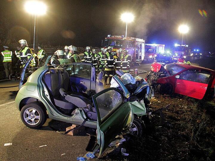 Rettungskräfte und zwei zerstörte Fahrzeuge stehen an einer Unfallstelle. Foto: Josef Reisner/dpa/Archivbild