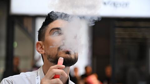 Ein Verk&auml;ufer einer E-Zigaretten-Firma nutzt bei der Dortmunder Messe Intertabac demonstrativ eine E-Zigarette. Der Verkauf dieser Produkte boomt. (Archivbild)