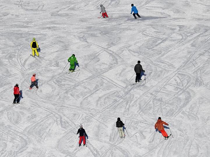 Skifahrer fahren bei Sonnenschein auf einer Skipiste. (Archivbild)