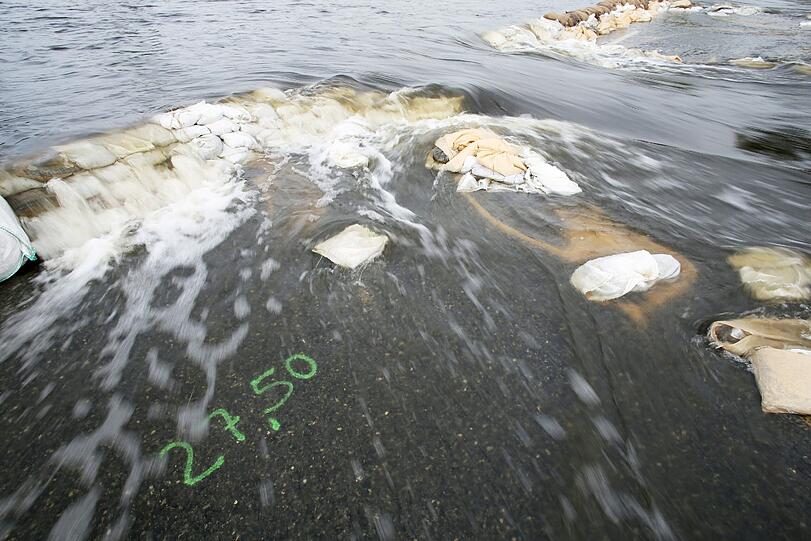 Ein Hilfsdamm aus Sandsäcken und eine Höhenmarke werden am 14.06.2013 auf der Landstraße zwischen Wulkau (Sachsen-Anhalt) und dem Nachbarort Kamern vom Hochwasser überspült. Durch den Deichbruch bei Fischbeck im Landkreis Stendal strömt das Hochwasser weiter Richtung Osten und überflutet große Teile der Region.