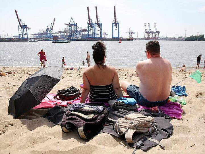 Am Elbstrand in Hamburg: Ausflügler sitzen bei hochsommerlichen Temperaturen am Strand von Övelgönne.