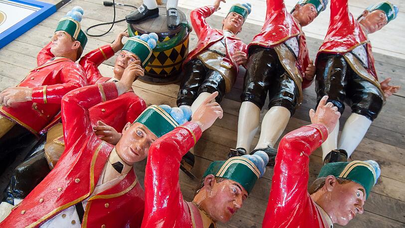 Acht Schäfflertanz-Figuren liegen vor ihrer Montage auf dem Boden.