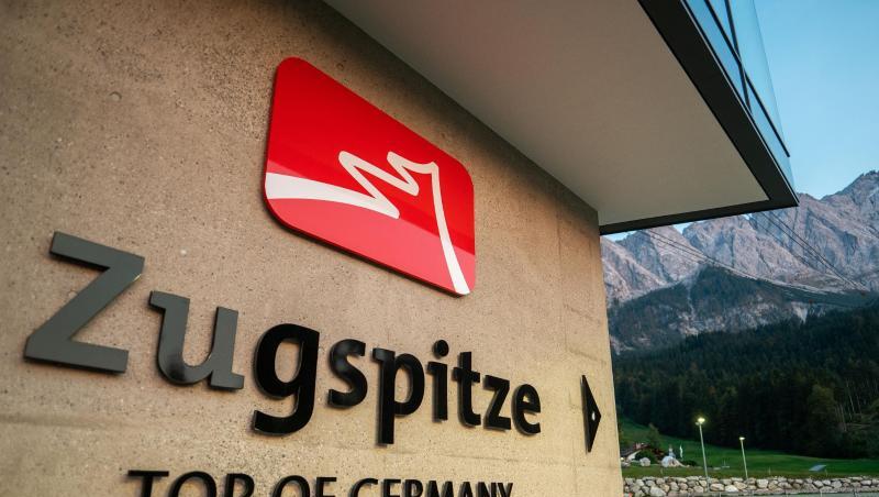 Ein Fahrradfahrer radelt nach Sonnenuntergang am Hinweis auf die Zugspitze entlang.