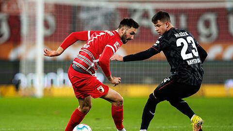 Augsburgs Dion Beljo (l) im Zweikampf mit Leverkusens Adam Hlozek.