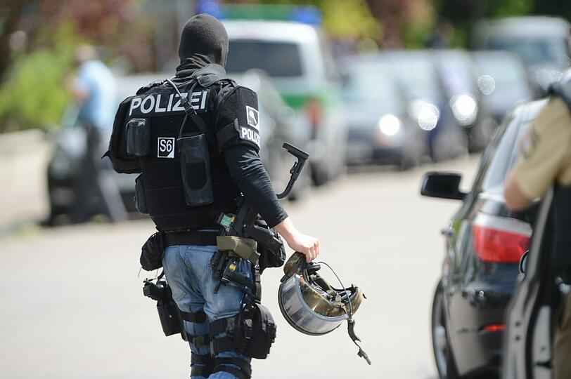 Ein Polizist eines Sondereinsatzkommandos bereitet sich vor der Lindenschule in Memmingen auf seinen Einsatz vor (Foto vom 22.05.12).