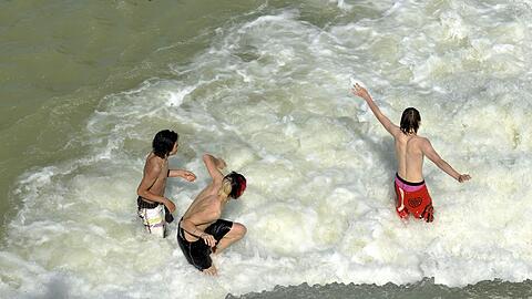Riesengroßes &ndash; und sogar erlaubtes &ndash; Badevergnügen in der Isar: Die drei Buben tollen am Flaucher im Wasser &ndash; also an einem von vier freigegebenen Bereichen im Stadtgebiet.