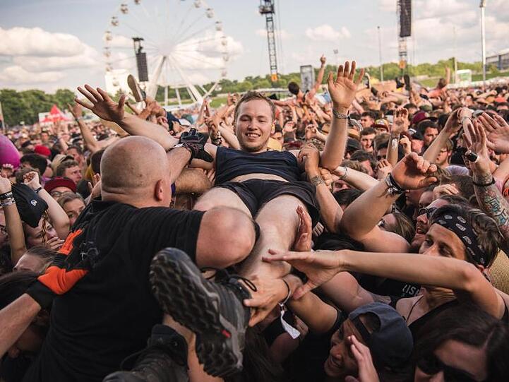 Security-Mitarbeiter heben während des Auftritts der Band "Rise Against" einen Fan aus der Menge. Foto: Nicolas Armer/Archiv