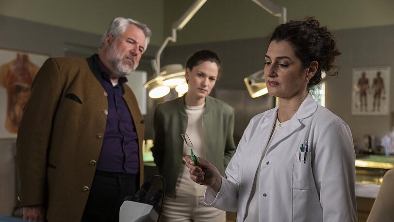 Hauptkommissar Stadler (Dieter Fischer, l.) und Hauptkommissarin Beck (Michaela Weingartner, M.) sprechen mit Dr. Dimos (Anastasia Papadopoulou, r.) in der Rechtsmedizin, die sie über eine neue Spur im Zuge des Obduktionsberichts informiert. Die Ermittlungsschritte gehen in der Serie wesentlich schneller als in der Realität. Hauptkommissar Stadler (Dieter Fischer, l.) und Hauptkommissarin Beck (Michaela Weingartner, M.) sprechen mit Dr. Dimos (Anastasia Papadopoulou, r.) in der Rechtsmedizin, die sie über eine neue Spur im Zuge des Obduktionsberichts informiert. Die Ermittlungsschritte gehen in der Serie wesentlich schneller als in der Realität.