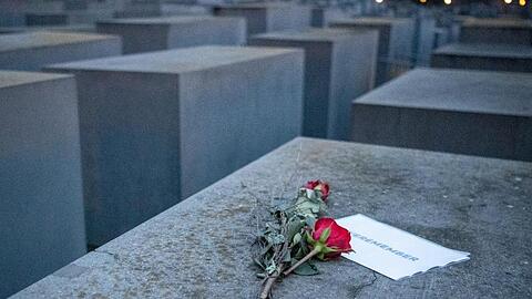 Rosen liegen mit einem Zettel mit der Aufschrift "#weremember" am Holocaust-Mahnmal in Berlin.