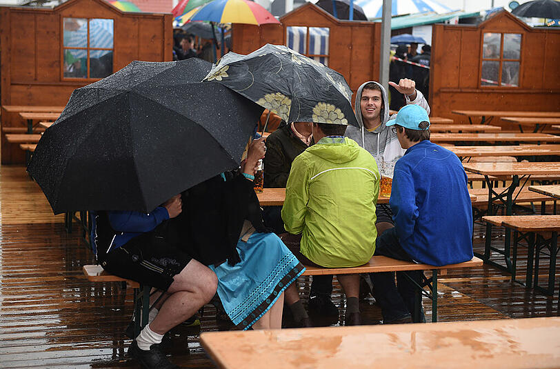 Um knapp vor 15 Uhr war es soweit: alle Zelte dicht. Und so nahmen diese Wiesnbesucher ihre erste Maß eben im Biergarten zu sich - im Regen.