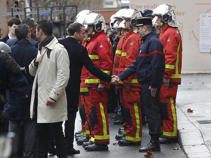 Emmanuel Macron, Präsident von Frankreich, gibt am Tag nach den Ausschreitungen in Paris einem Feuerwehrmann die Hand.