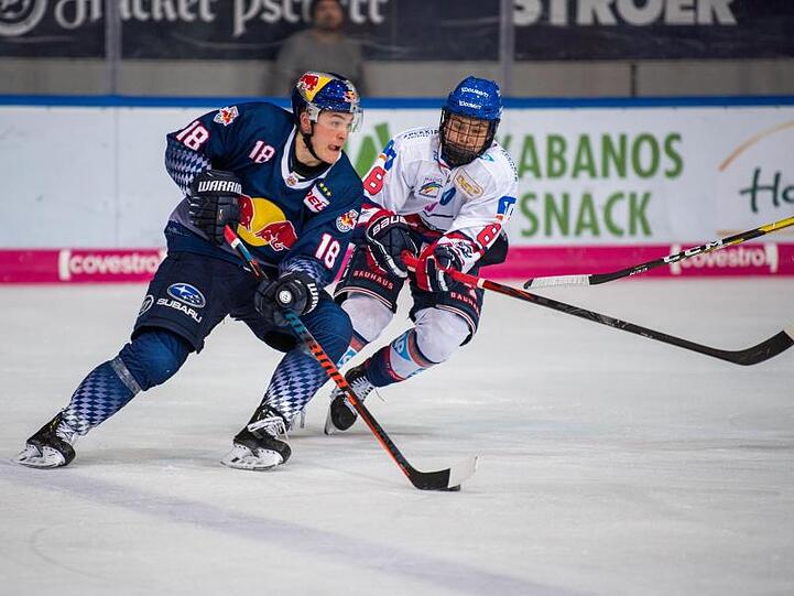 Justin Schütz von Red Bull München und Tim Stützle von Adler Mannheim (l-r.) bemühen sich um den Puck. Foto: Lino Mirgeler/dpa