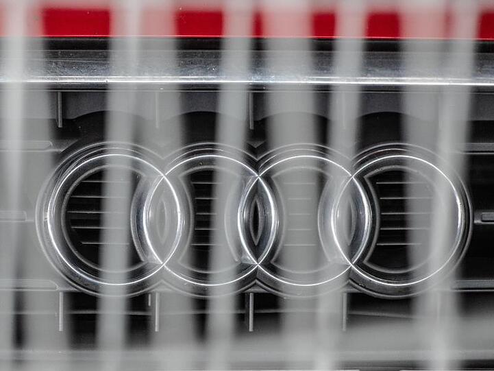 Hinter einem Metallzaun steht ein Audi mit dem Logo des Autoherstellers auf der Motorhaube in einem Parkhaus. Foto: Armin Weigel/dpa