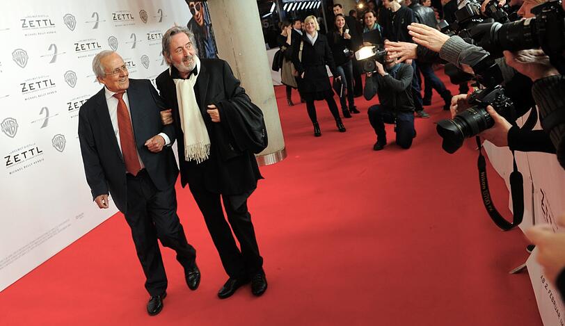 Wer stützt hier eigentlich wen? Dieter Hildebrandt (links), der in seiner Zettl-Filmrolle als Paparazzo-Fotograf Herbie Fried im Rollstuhl sitzen muss, schlendert mit Regisseur Helmut Dietl über den roten Teppich.