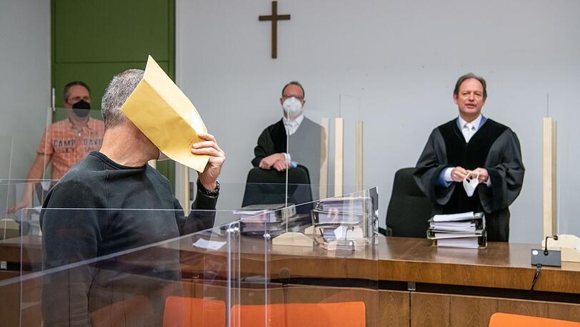 Der Angeklagte hält sich zum Auftakt im Prozess wegen fünffachen Mordversuchs gegen ihn einen Briefumschlag vor das Gesicht.