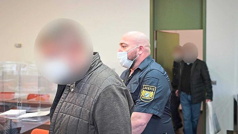 Einer der Angeklagten wird in den Saal geführt.