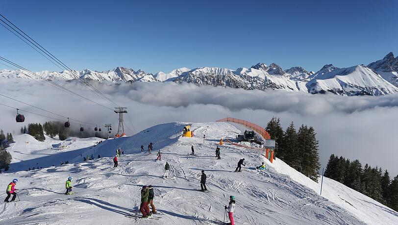 Wintersportler fahren auf dem Fellhorn &uuml;ber den Wolken im Sonnenschein.