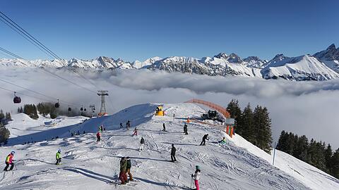 Wintersportler fahren auf dem Fellhorn über den Wolken im Sonnenschein.