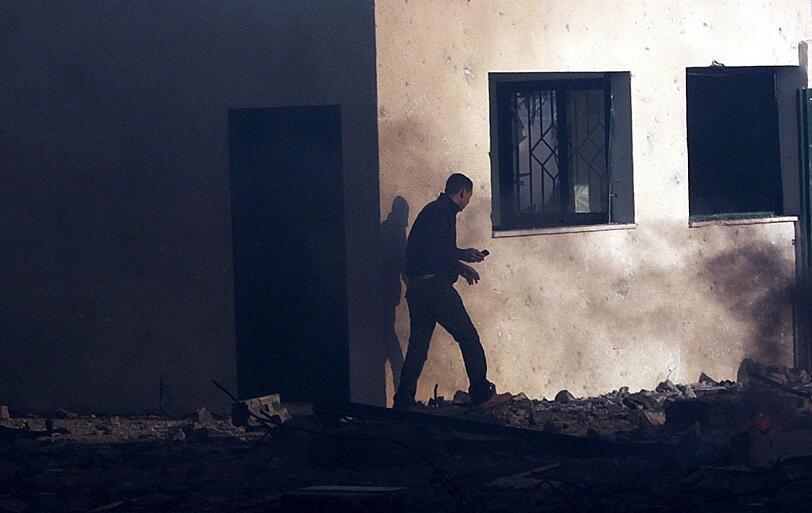 Ein Hamas-Kämpfer untersucht den zerstörten Ministerialbau, in den am Morgen eine israelische Fliegerbombe einschlug.
