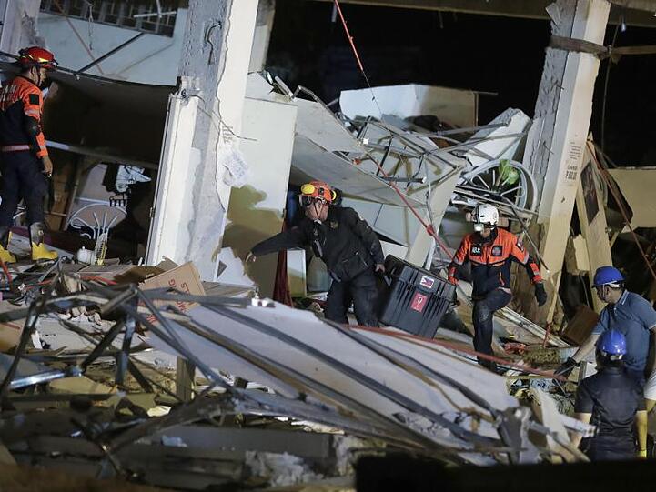 Rettungskräfte suchen in einem eingestürzten Gebäude nach Überlebenden.