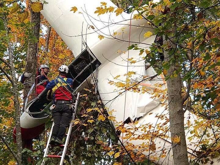 Mitarbeiter der Bergwacht stehen während Bergungsarbeiten an einem Segelflugzeug auf einer langen Leiter. Foto: Dominik Bartl/dpa