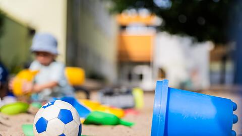 Ein Kind spielt in einem Sandkasten - wo haben dessen Eltern wohl Eimerchen, Schaufeln und den kleinen Ball gekauft, im Internet oder im Geschäft?