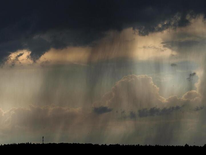 Dunkle Gewitterwolken und Regen sind von Ebing (Bayern) aus zu sehen. Foto: Nicolas Armer/Archivbild