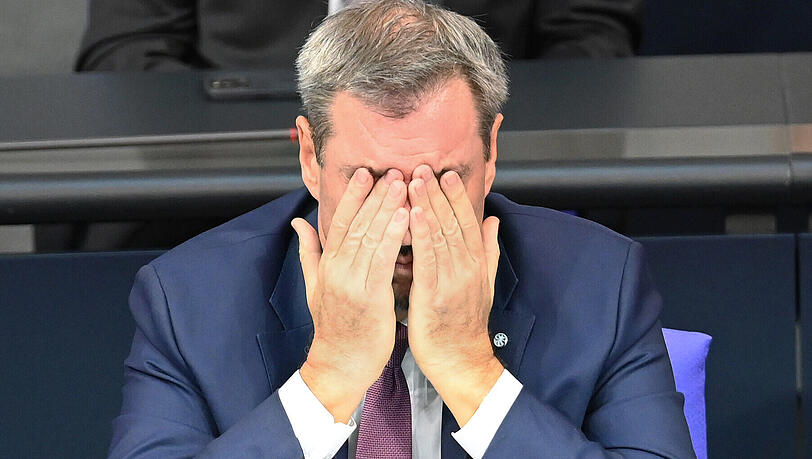 Markus Söder (CSU), Ministerpräsident von Bayern, nimmt an der Sitzung des Bundestags teil und hält die Hände vor dem Gesicht.