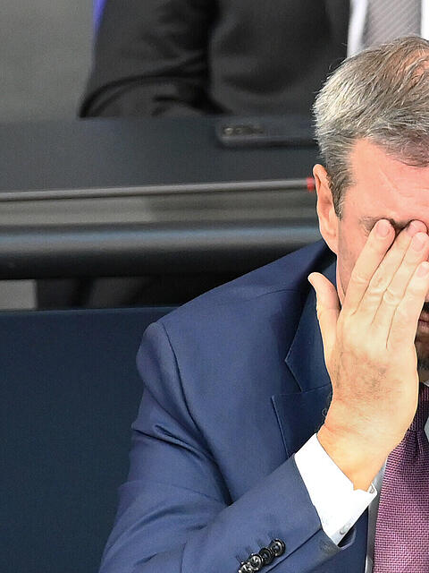 Markus Söder (CSU), Ministerpräsident von Bayern, nimmt an der Sitzung des Bundestags teil und hält die Hände vor dem Gesicht.