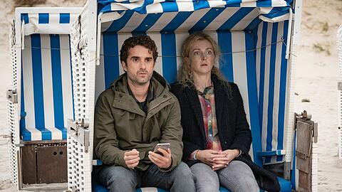 "Nord Nord Mord: Sievers und die Tote im Strandkorb": Hinnerk (Oliver Wnuk) setzt sich direkt neben die Leiche von Marion Caspary (Lola Krauss).