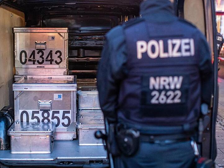 Polizeibeamte sichern kistenweise Beweise nach einer Durchsuchung in einem Geschäft.