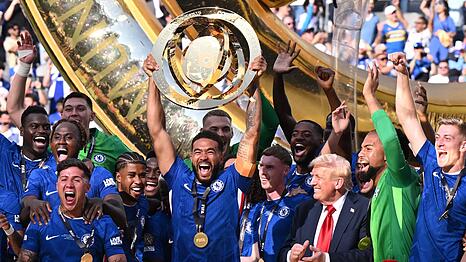 US-Präsident Donald Trump bleibt einfach bei den Chelsea-Spielern auf dem Siegerpodest und applaudiert ihnen.