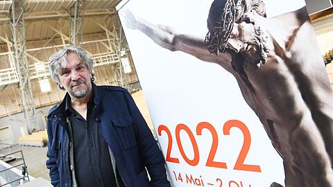 Christian Stückl, Spielleiter der Passionsspiele, steht neben dem neuen Plakat für die Passion 2022.