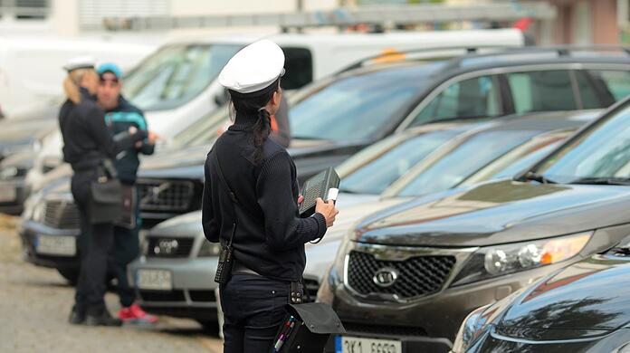 Autofahrer parkten falsch auf der Theresienwiese.  Ein Polizist stellt Strafzettel aus und die Stadt möchte diesen Prozess automatisieren.