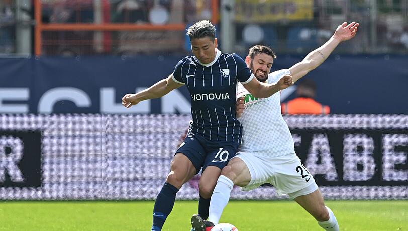 Bochums Takuma Asano (l) und Augsburgs Daniel Caligiuri kämpfen um den Ball.
