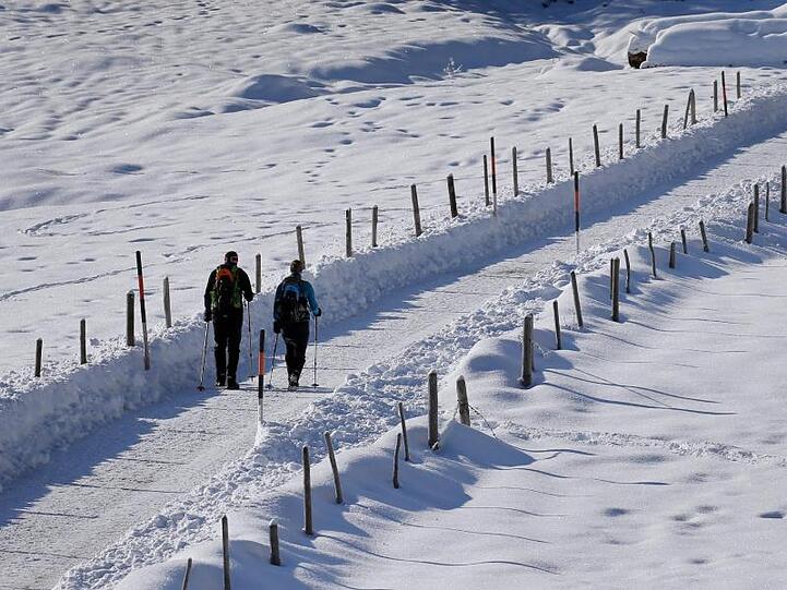 Weiße Pracht: Wanderer gehen bei Sonnenschein durch eine schneebedeckte Landschaft im bayerischen Bad Hindelang.